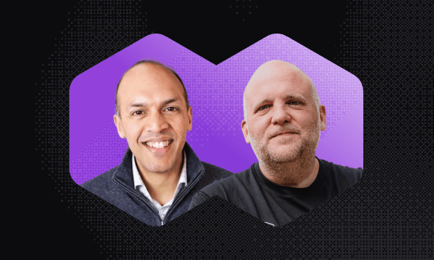 Two men smiling against a purple background within hexagonal frames. One wears a dark sweater, the other a black shirt.
