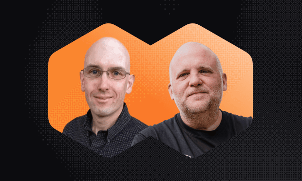 Two men with shaved heads are side by side, smiling against an orange, hexagonal background with a dotted pattern.